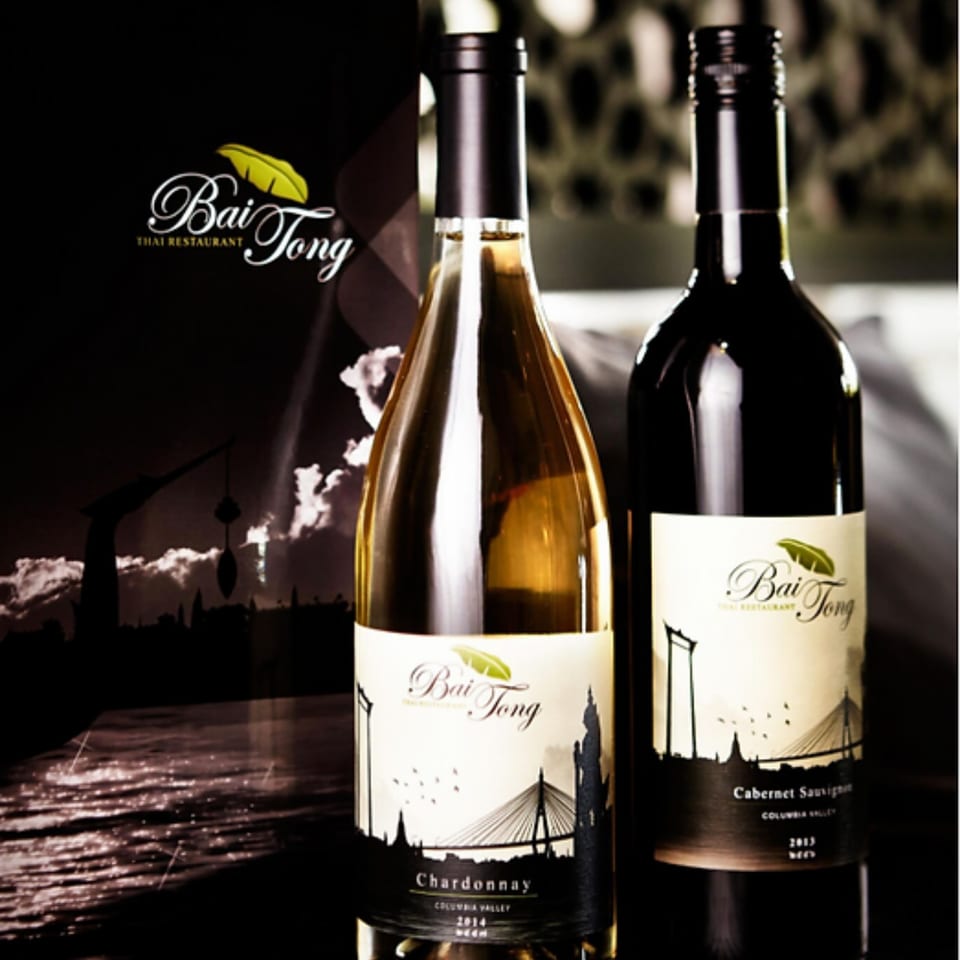 Two Bai Tong branded wine bottles, Chardonnay and Cabernet Sauvignon, with a cityscape label.
