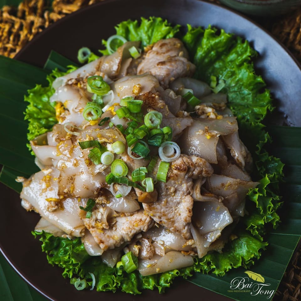 Bai Tong Thai Street Cafe's Pad See Ew with wide noodles, chicken, and green onions on lettuce.